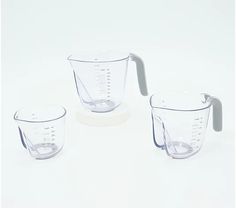 three measuring cups sitting next to each other on a white surface with one measuring cup in the middle