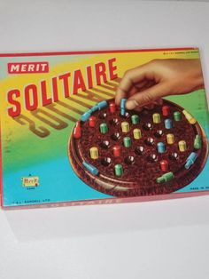 a game board with the words solitaire written on it and a hand placing dices in front of it