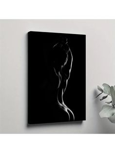 a black and white photo of a woman's torso on a wall next to a plant