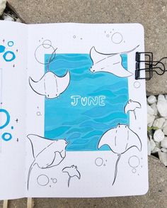 an open notebook with the words june written on it next to some rocks and pebbles