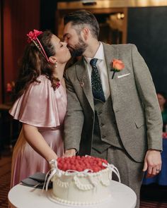 a man and woman kissing in front of a cake