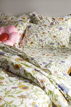 a bed with floral sheets and pillows on it