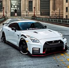 a white nissan sports car parked in front of a large building with columns on it