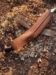 an old knife laying on the ground covered in wood shavings and mulch