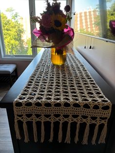 a vase filled with flowers sitting on top of a wooden table next to a window