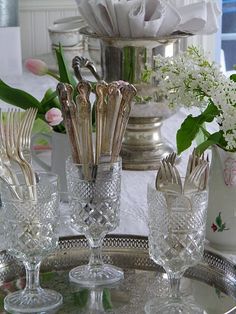 silverware is sitting on a tray with flowers in vases and other glassware