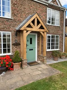 a green front door with white windows and wooden frame on a brick house in england