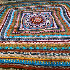 a multicolored crocheted blanket is laying on the floor