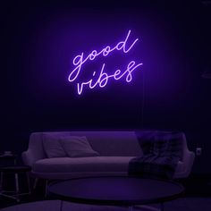 a purple neon sign that says good vibes on the wall next to a couch