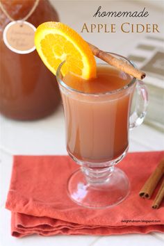 an orange slice sitting on top of a drink in a glass next to cinnamon sticks