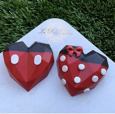 two red and black heart shaped cakes sitting on top of a white table next to green grass