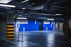 an empty parking garage with blue and yellow painted on the walls, black and white striped flooring