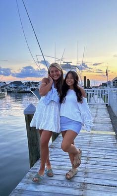 two girls standing on a dock at sunset