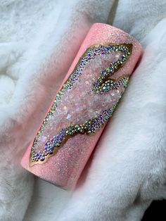 a pink case with glitter on it sitting on top of a white fur covered blanket