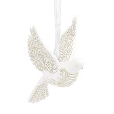 a white ceramic bird ornament hanging from a string on a white background with an intricate design