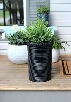 two black and white planters sitting on top of a wooden table