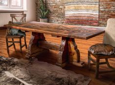 a wooden table and two chairs in front of a brick wall with rugs on the floor