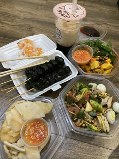 several plastic containers filled with food on top of a wooden table next to a drink