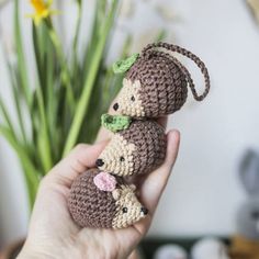 two small crocheted mice sitting on top of each other in front of a plant