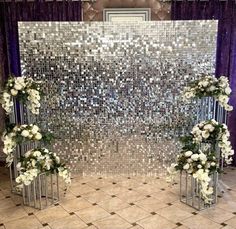 two vases filled with white flowers sitting on top of a floor next to a mirror wall