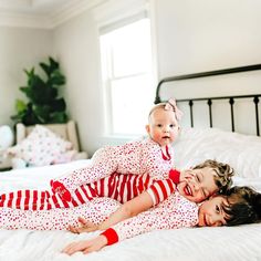 two young children laying on top of a bed in matching red and white pjss