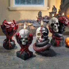 three candles with skulls and roses on them sitting next to pumpkins in front of a fireplace