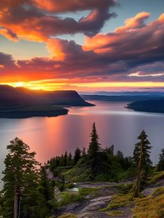 the sun is setting over a lake with mountains and trees in the background, as seen from an overlook point