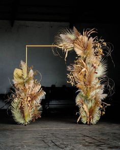 two vases with dried flowers in front of a black background and a gold frame