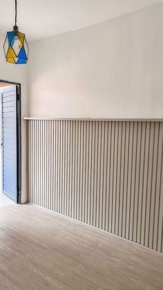 an empty room with wooden flooring and blue shutters on the wall, next to a closed door