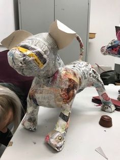 a woman is working on an animal made out of newspaper