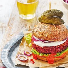 a large hamburger sitting on top of a plate next to a bowl of salad and pickles