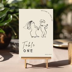 a table sign sitting on top of a wooden easel next to a potted plant