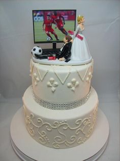 a wedding cake with a tv and soccer player on the top tier is decorated in white frosting