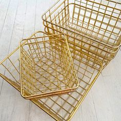 three gold metal baskets sitting on top of a white wooden floor next to each other