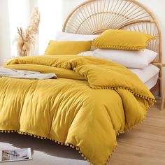 a bed with yellow sheets and pillows in a room next to a white rug on the floor