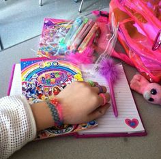 a child's hand writing on a notepad next to other toys and supplies