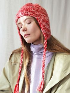 a woman with her eyes closed wearing a red knitted beanie hat and scarf