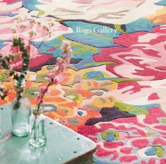 two vases filled with flowers sitting on top of a table next to a rug