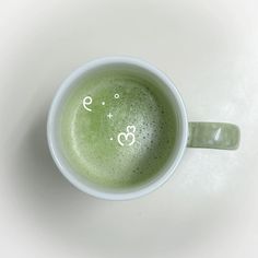 a cup filled with green liquid on top of a white table