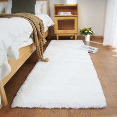 a white rug on the floor next to a bed