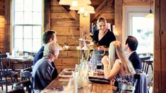 a group of people sitting around a wooden table in a room with wood paneling