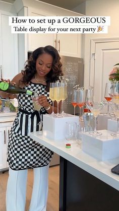 a woman standing in front of a counter filled with glasses