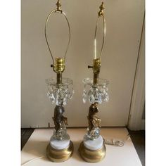 two glass and brass table lamps sitting on top of a white surface