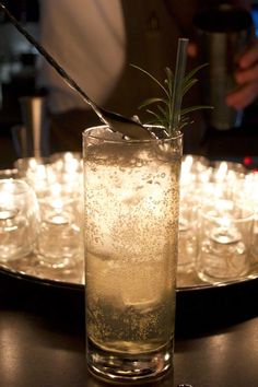 a glass filled with ice and water sitting on top of a table next to glasses