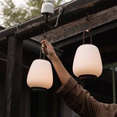 a woman is holding two lamps up to the ceiling