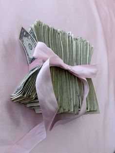 a bunch of money is wrapped in pink ribbon