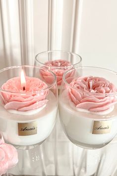 three candles with pink roses in them sitting on a table