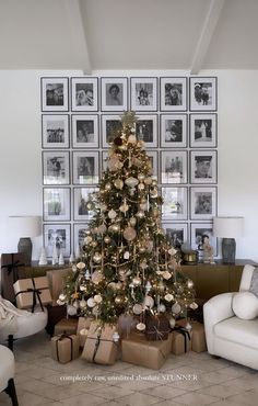 a decorated christmas tree in a living room with pictures on the wall and presents under it