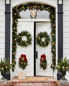 two christmas wreaths on the front door of a house