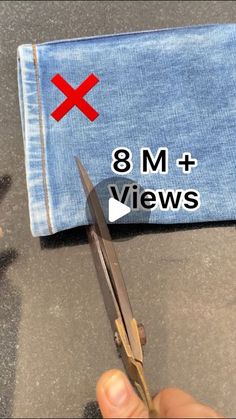 a pair of scissors is being used to cut the bottom of a pair of jeans